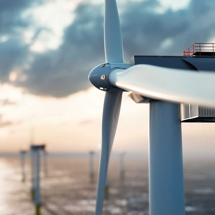A close-up of a wind turbine blade against a cloudy sky over the ocean, highlighting renewable energy technology.